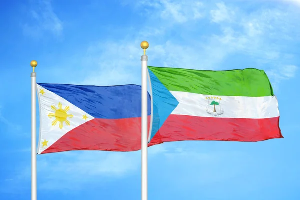 Philippines and Equatorial Guinea two flags on flagpoles and blue cloudy sky background