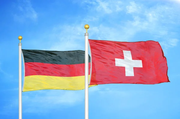 ドイツとスイスの旗竿と青空の背景に2つの旗 — ストック写真