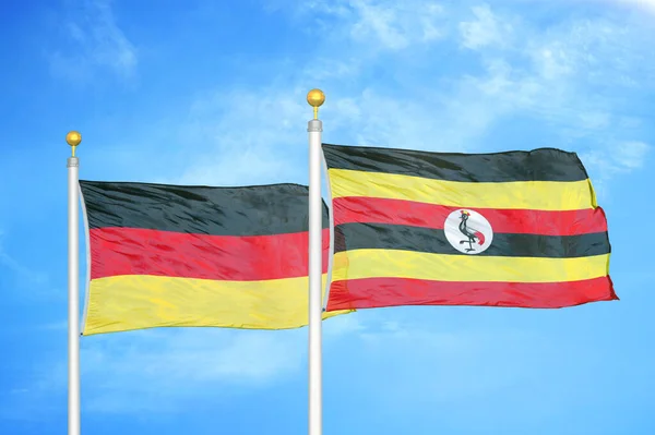 Duitsland Oeganda Twee Vlaggen Vlaggenmasten Blauwe Bewolkte Lucht Achtergrond — Stockfoto