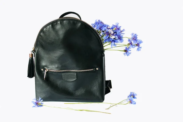 Mavi çiçekli beyaz arka plan üzerinde duran sırt çantası siyah