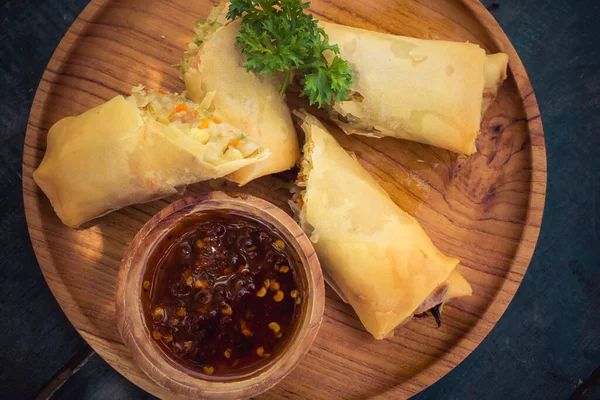 Kereste tabağında ve sosta Asya yemekleri.