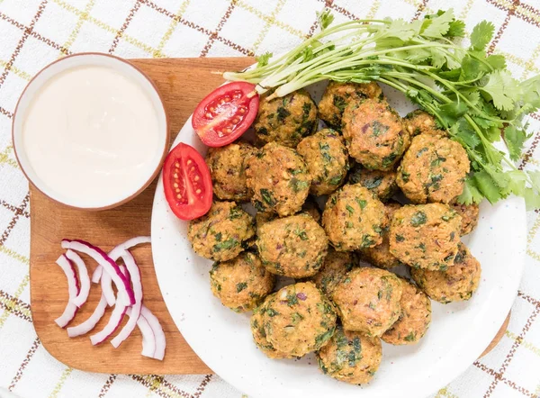 Falafel-Bällchen und frisches Gemüse auf Teller mit Wurst auf Holzbrett — Stockfoto