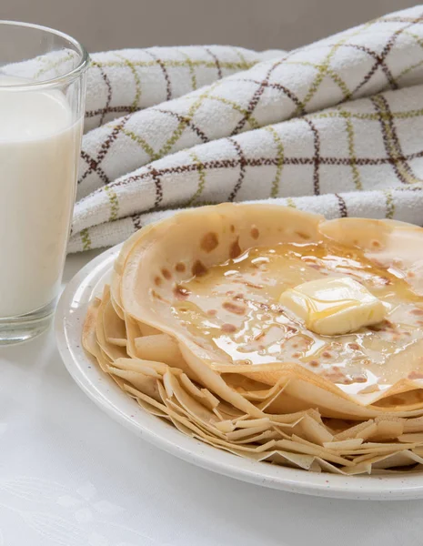 Dunne pannenkoeken met boter en honing op witte plaat — Stockfoto