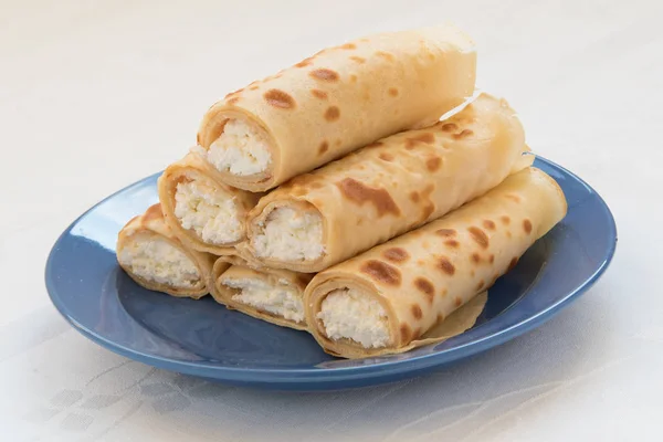 Pancake rolls with cottage cheese on blue plate.