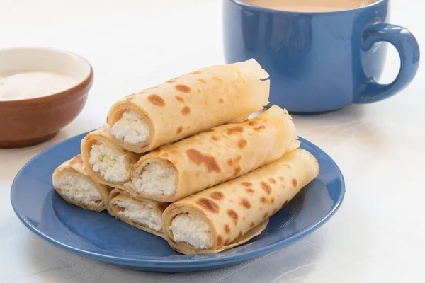 Pannenkoeken rolletjes met kwark op blauwe plaat. — Stockfoto