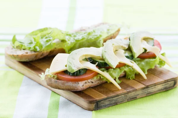 アボカド、チーズ、サラダの葉とトマトのオープン サンドイッチ — ストック写真