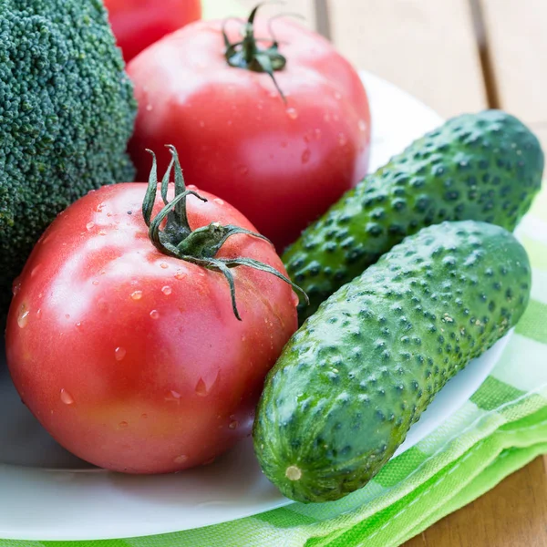 Legumes crus frescos, dois tomate, brócolis e pepino na placa branca . — Fotografia de Stock