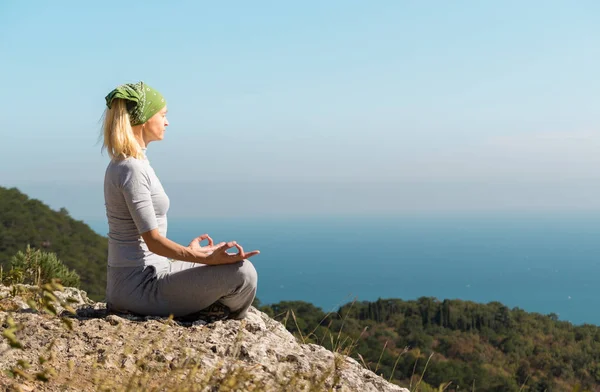 Yoga Donna è seduto sulla cima della montagna e medita Immagine Stock