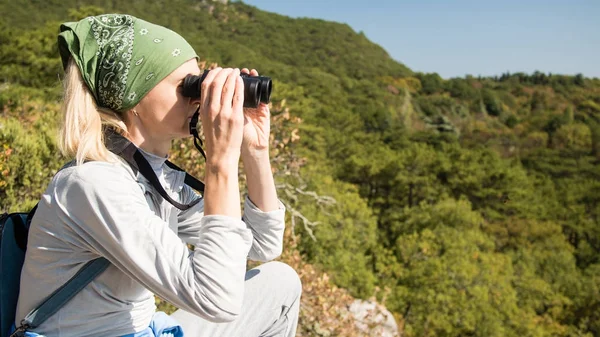 Sarışın bir kadın turist dürbün dağlar üzerinde seyir. Seyahat kavramı.
