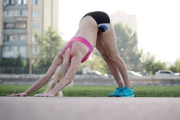 Fleksibel kvinde praktiserer yoga og gør ned hund udgør - Stock-foto
