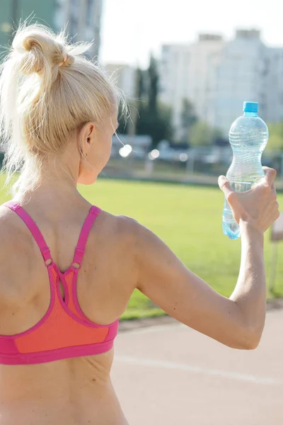 Женщина держит в руках бутылку с водой — стоковое фото