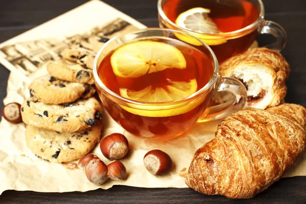 Siyah çay limon, taze ekmek ve bej bir kağıt üzerinde fındık