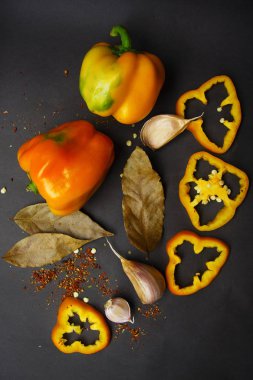 Sarı tatlı biber - tüm ve baharat ve gri bir arka plan üzerine sarımsak ile dilimlenmiş