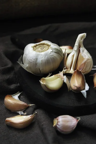 Garlic and cloves of garlic on a black board and a gray linen napkin in rustic style