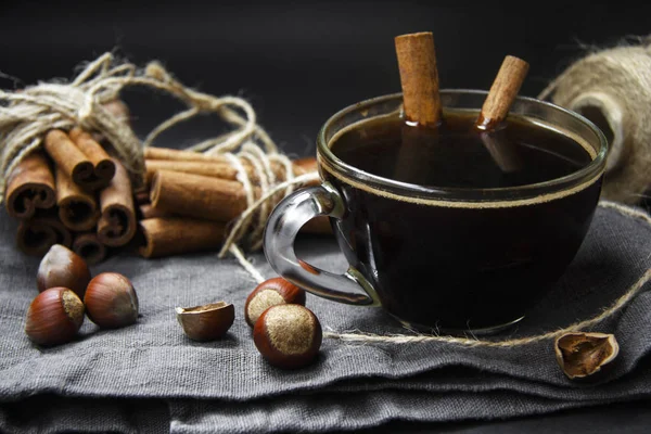 Gri bir arka plan üzerinde fincan kahve, fındık içi ve tarçın sopa