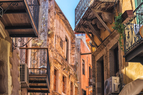 Old narrow street with stone walls and wooden windows in Chania city, Greece