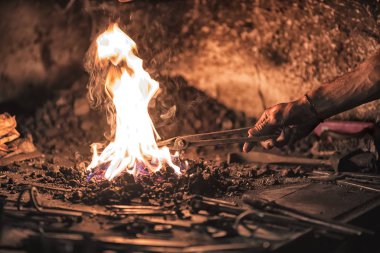 Yanan kömürleri, aletleri ve parlayan metal işçiliği olan demirci ocağı..