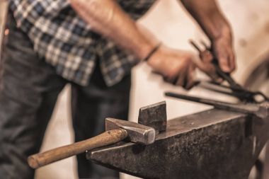 Yanan kömürleri, aletleri ve parlayan metal işçiliği olan demirci ocağı..