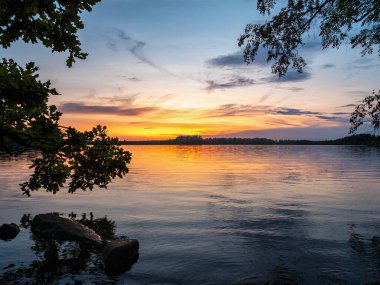 Lakeside Günbatımı 'nın resmi Ağaçlar ve mavi gökyüzü