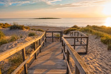 Okyanus manzaralı kum tepelerinin üzerinde Baltık Denizi 'ndeki ahşap patika. Yaz akşamında gün batımı.