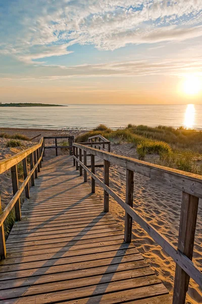 Wooden path at Baltic sea over sand dunes with ocean view, sunset summer evening