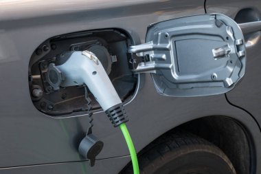 Şarj kablosu takılı elektrikli araba elektrik prizinin yakın plan görüntüsü.