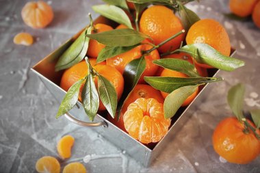 Çelik sepet ve soyulmuş bir Mandarin gri taş yaprakları ile taze mandalina