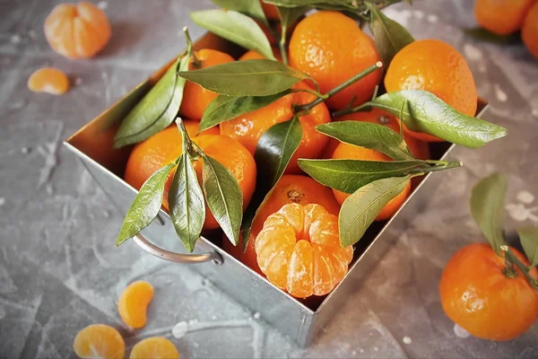 Çelik sepet ve soyulmuş bir Mandarin gri taş yaprakları ile taze mandalina