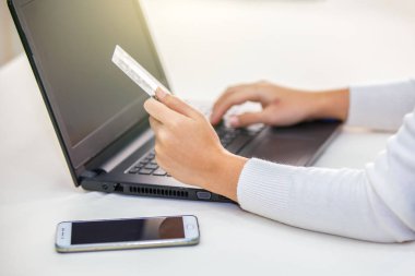 Kredi kartı tutan ve dizüstü bilgisayar kullanan eller. İnternetten alışveriş
