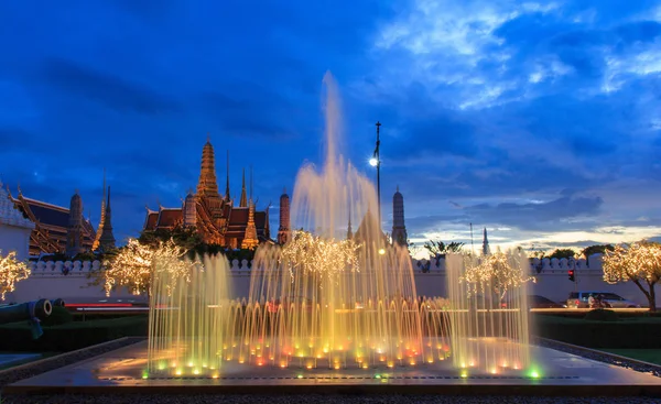 Cerca de la fuente en la luz de la noche hito de Sanam Luang y Emerald Buddha Temple (Wat Phra Kaew) fondo, Bangkok, Tailandia —  Fotos de Stock