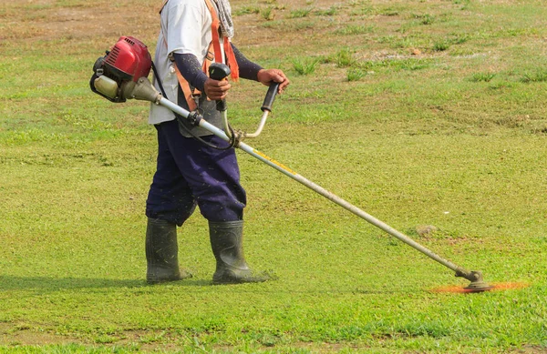 Arbetare klippa gräs i trädgården med ogräs trimmer — Stockfoto