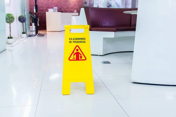 Lobby floor with mop bucket and "caution cleaning progress" signs, selective focus sign on the front. — Stock Photo, Image