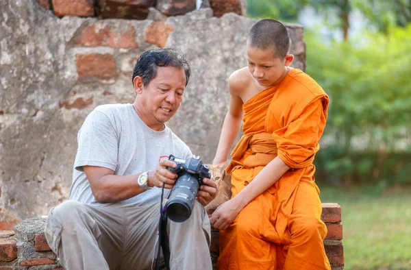 Homem velho fotógrafo e jovem novato à procura de câmera de foto no templo antigo na província de Ayutthaya, Thailan — Fotografia de Stock