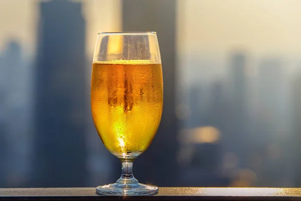 Ποτήρι μπύρας εναντίον θολή Ασιατική πόλη με όμορφα φώτα σε φόντο στο βράδυ — Φωτογραφία Αρχείου