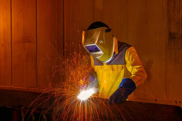 Worker with protective mask welding metal in warehouse industrial.