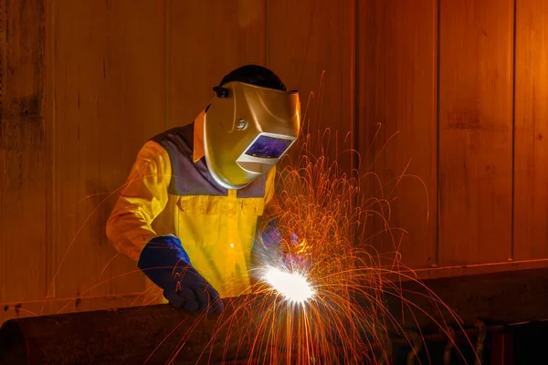 Worker with protective mask welding metal in warehouse industrial.