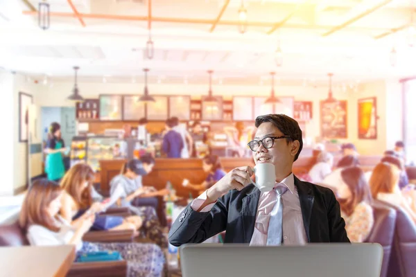 Güzel gülümseme bulanık kahve dükkanı arka planda dinlenme sırasında sıcak kahve içme ile mutlu Asya işadamı. — Stok fotoğraf