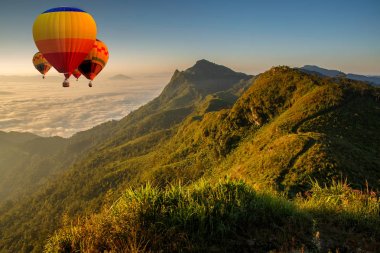 Renkli sıcak hava balonu üzerinde uçan Pha Tung dağda gündoğumu zamanında, Chiang Rai, Tayland.