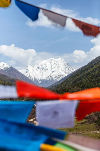 Snow góry w Chinach Poitou w Sertar County w Garze tybetańskiej autonomicznej prefekturze w Tybecie, Kham, Chiny, flagami modlitewnymi niewyraźne w pierwszym planie. Selektywny fokus na górze — Zdjęcie stockowe