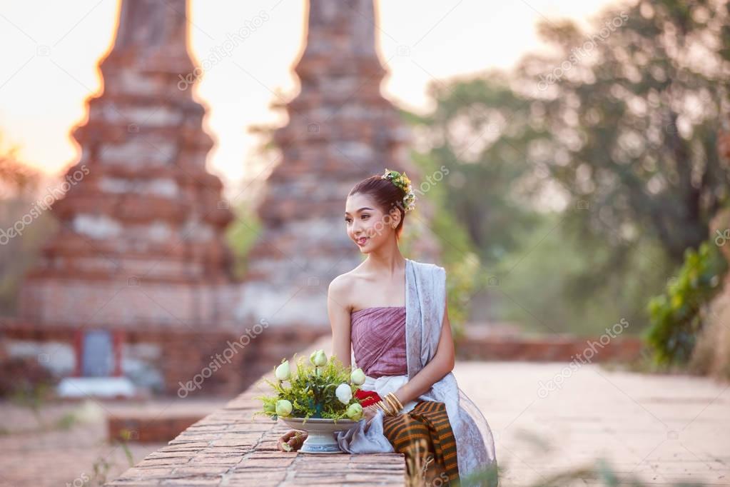Beautiful Thai girls in thai traditional costume trying to roll up lotus flower at sunset time