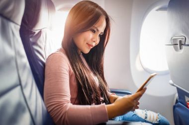 Asyalı kadın uçak içinde cep telefonu kullanımı