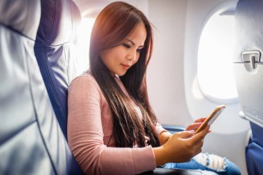 Asyalı kadın uçak içinde cep telefonu kullanımı