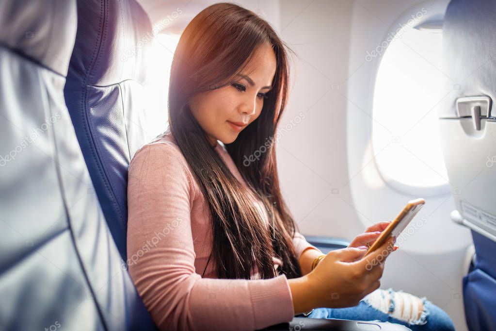 Asian woman use of mobile phone inside airplane