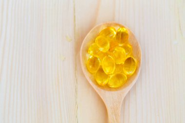 Omega 3 ve D vitamini içeren balık yağı kapsülleri ahşap kaplama, sağlıklı beslenme konsepti.