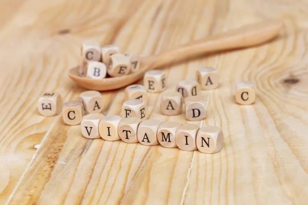 Close up vitamina parola fatta da lettere di legno sul tavolo e A B C D E sul cucchiaio di legno, concetto di salute — Foto Stock