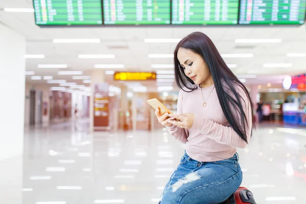 Asian woman sitting on the baggage use of mobile phone check in online ticket airline at international airport.
