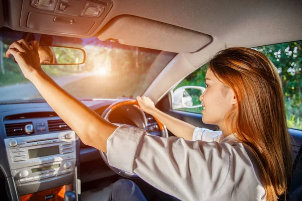 Young asian woman driver adjusting her rearview mirror in the car.