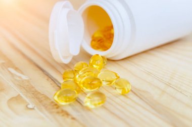Omega 3 ve D vitamini içeren balık yağı kapsülleri ahşap kaplama, sağlıklı beslenme konsepti.