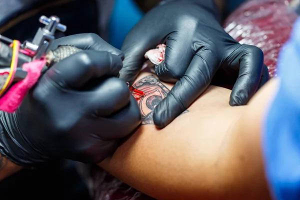 Close up tattoo artist demonstrates the process of getting black tattoo with paint. Master works in black sterile gloves. — Stock Photo, Image