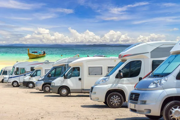 Karavan üst üste beyaz kum plaj ve mavi gökyüzü arka plan üzerinde park edilmiş kapatmak.